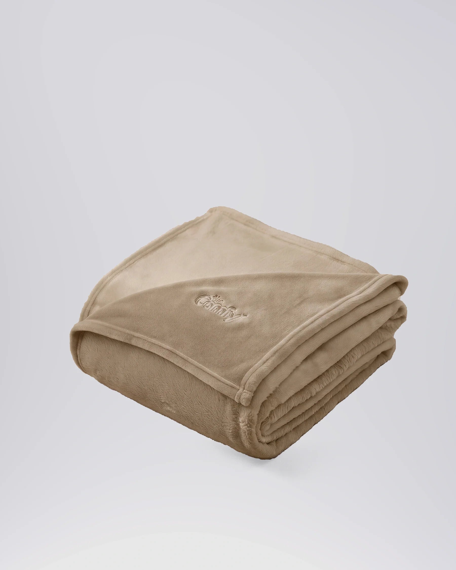 Folded tan oversized blanket with embroidered logo displayed on a matching neutral backdrop.