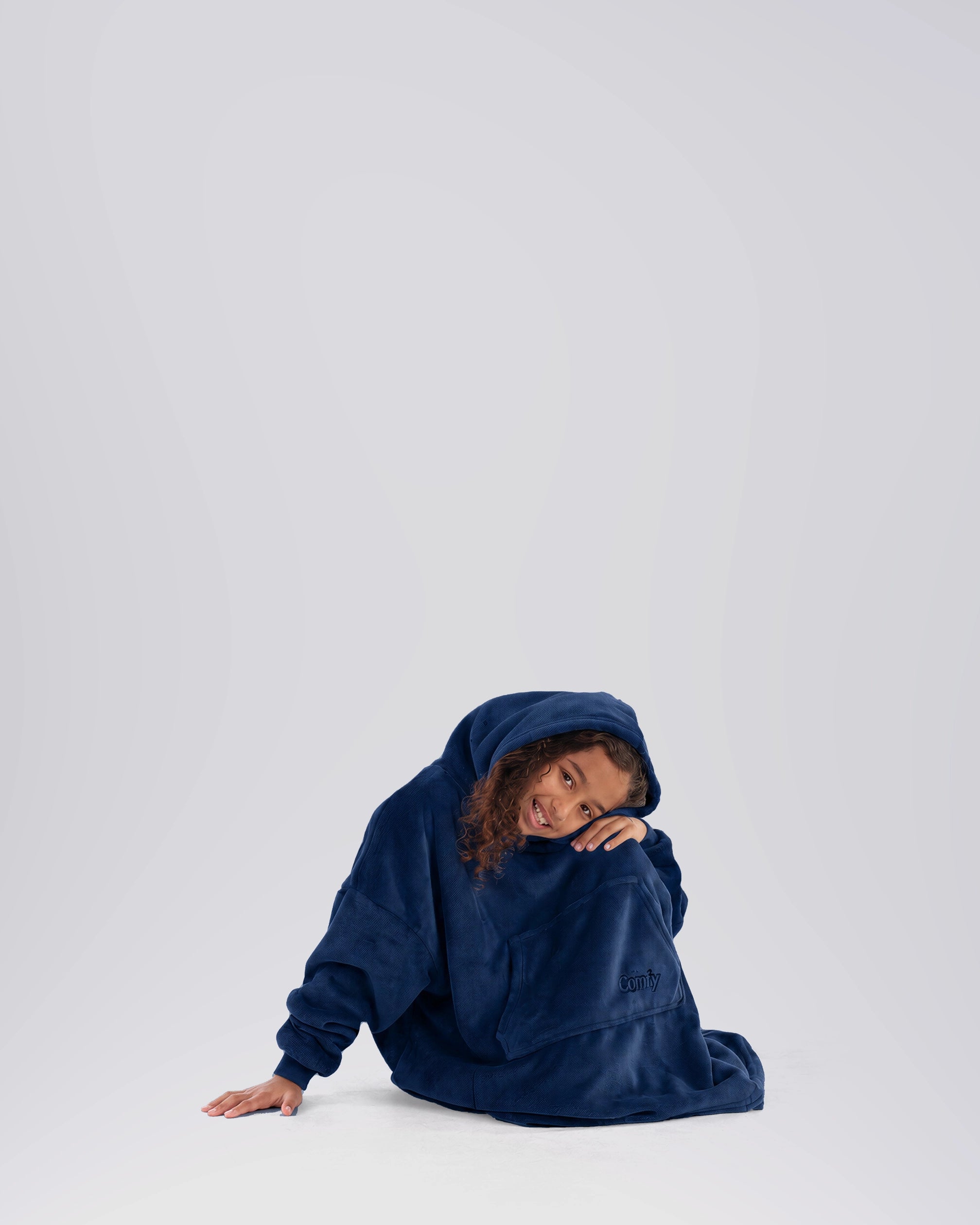 Child sitting comfortably in The Dream Jr. in Sky Blue, showing its relaxed fit and baby-blanket softness.
