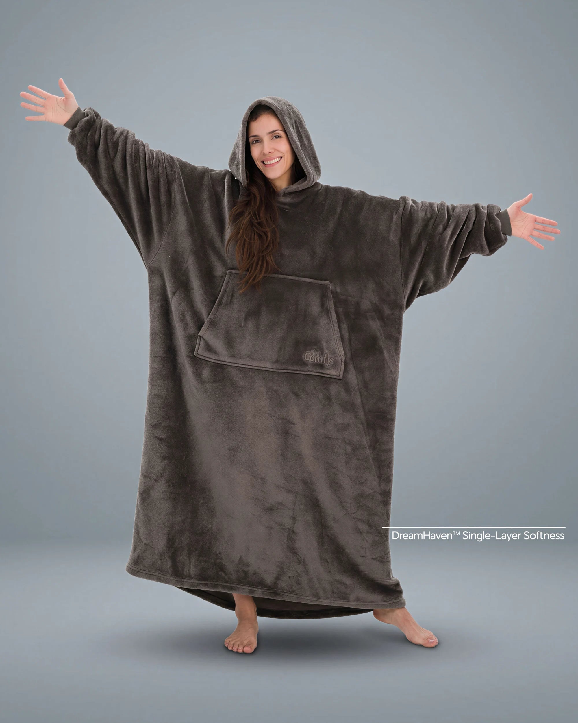 Woman standing with arms outstretched in The Dream Long wearable blanket in Dark Gray, showcasing the full-length silhouette and lightweight DreamHaven™ single-layer softness.