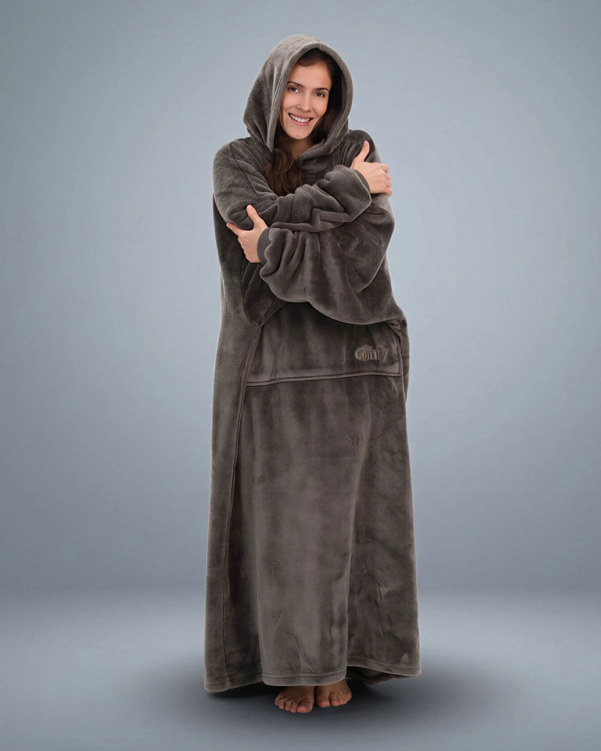 Woman wrapped comfortably in The Dream Long wearable blanket, emphasizing the extended length, oversized sleeves, and lightweight comfort for relaxing at home.
