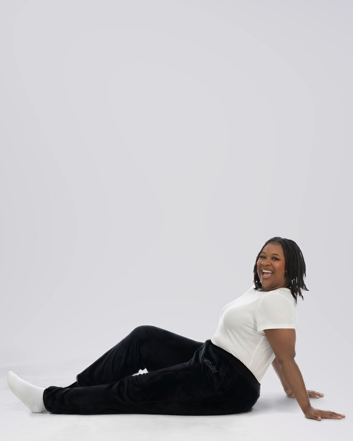 Model seated while wearing The Dream Pants in Black.