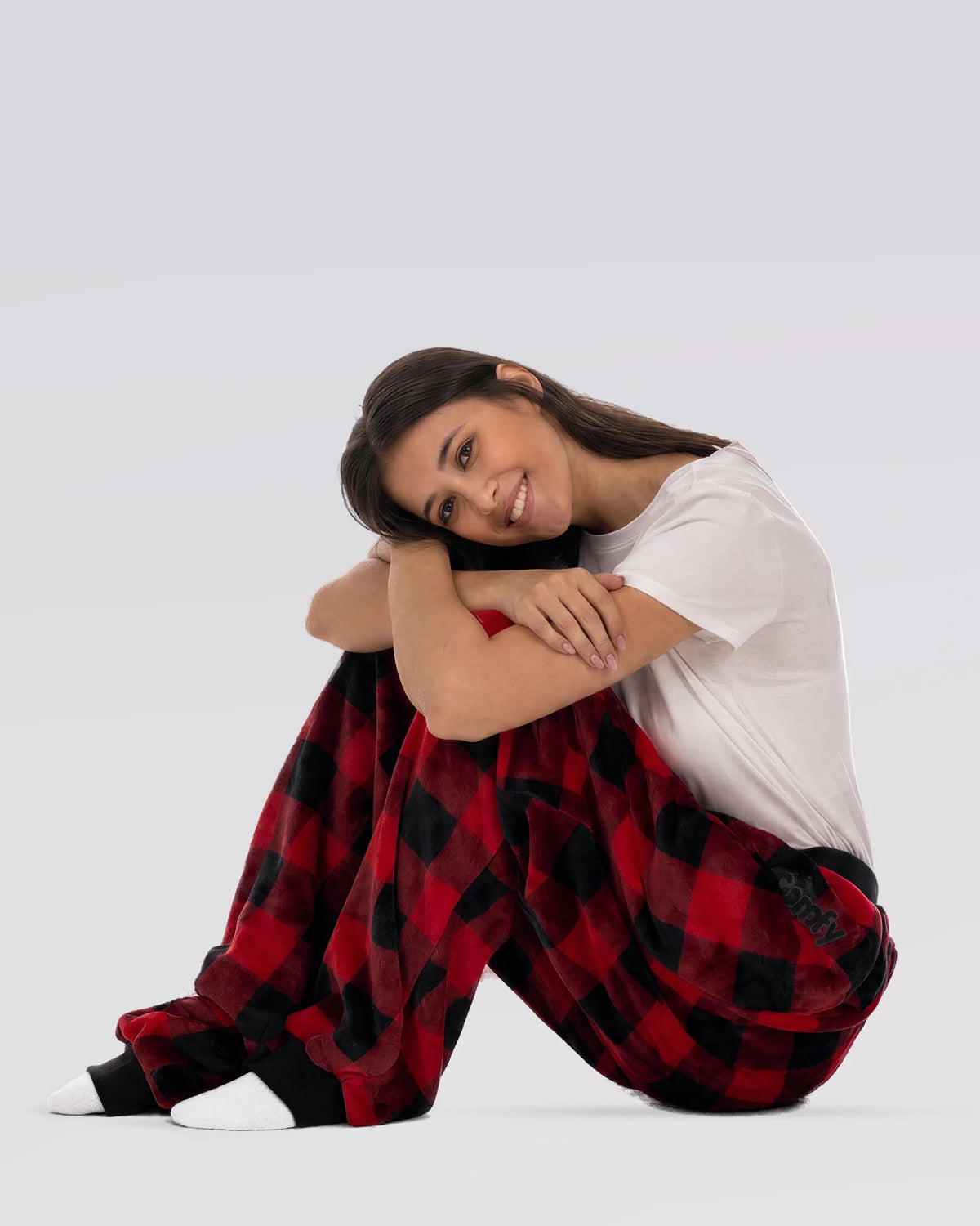 Woman sitting with knees hugged while wearing Dream Pants in Red Plaid, showcasing the cozy fit and soft plaid fabric.
