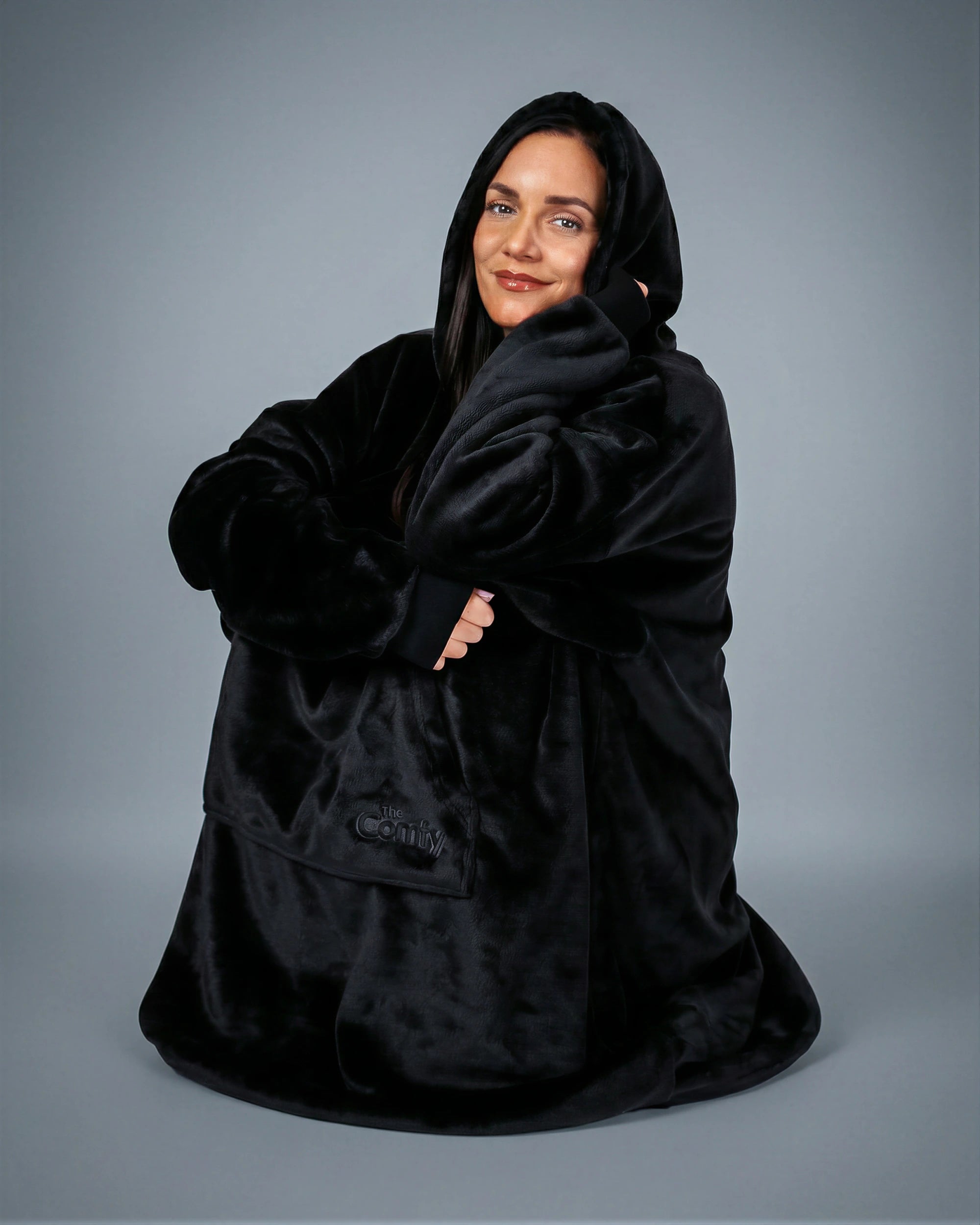 Model wrapped in The Dream wearable blanket in Black, highlighting the cozy oversized fit and relaxed comfort perfect for unwinding at home.