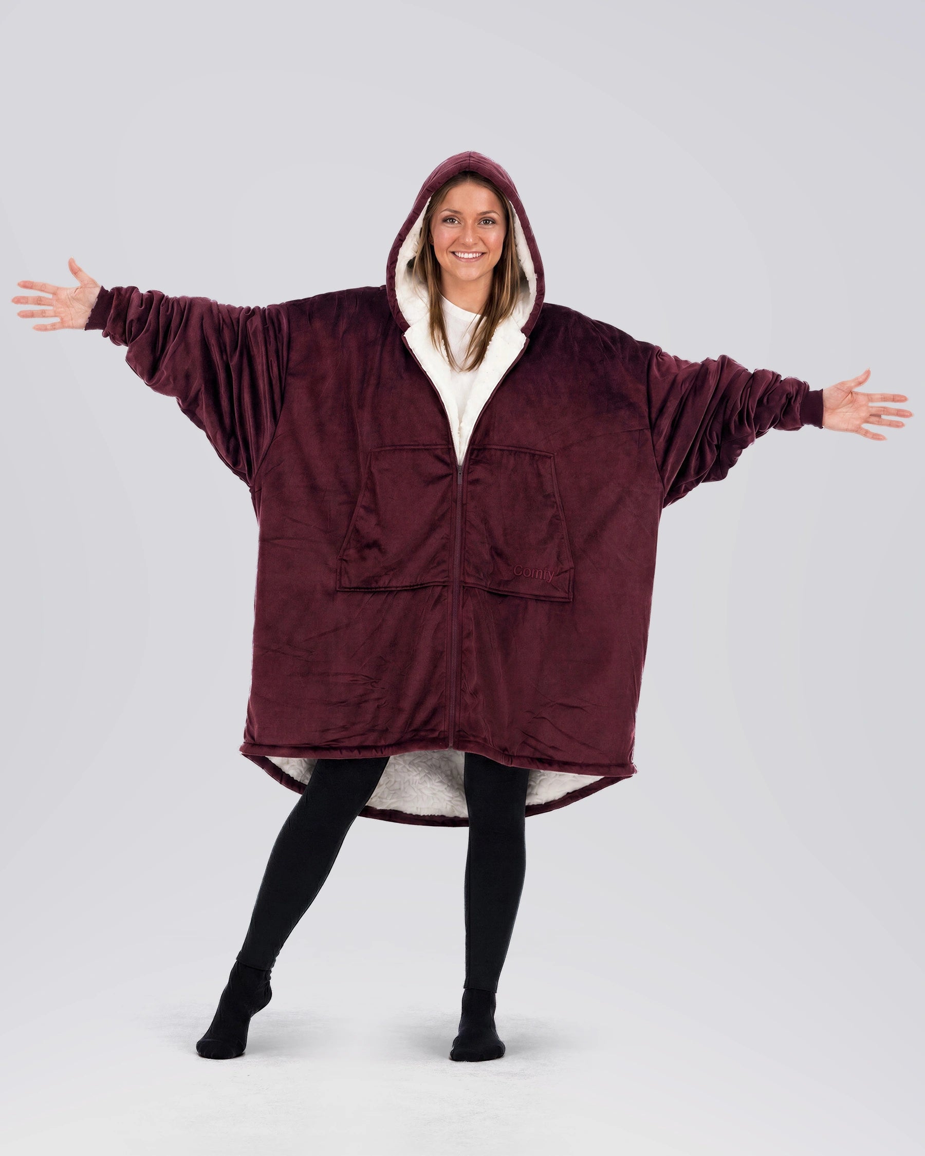 Person wearing The Original Full-Zip wearable blanket in Burgundy with arms outstretched, showcasing oversized fit and full-length zipper.