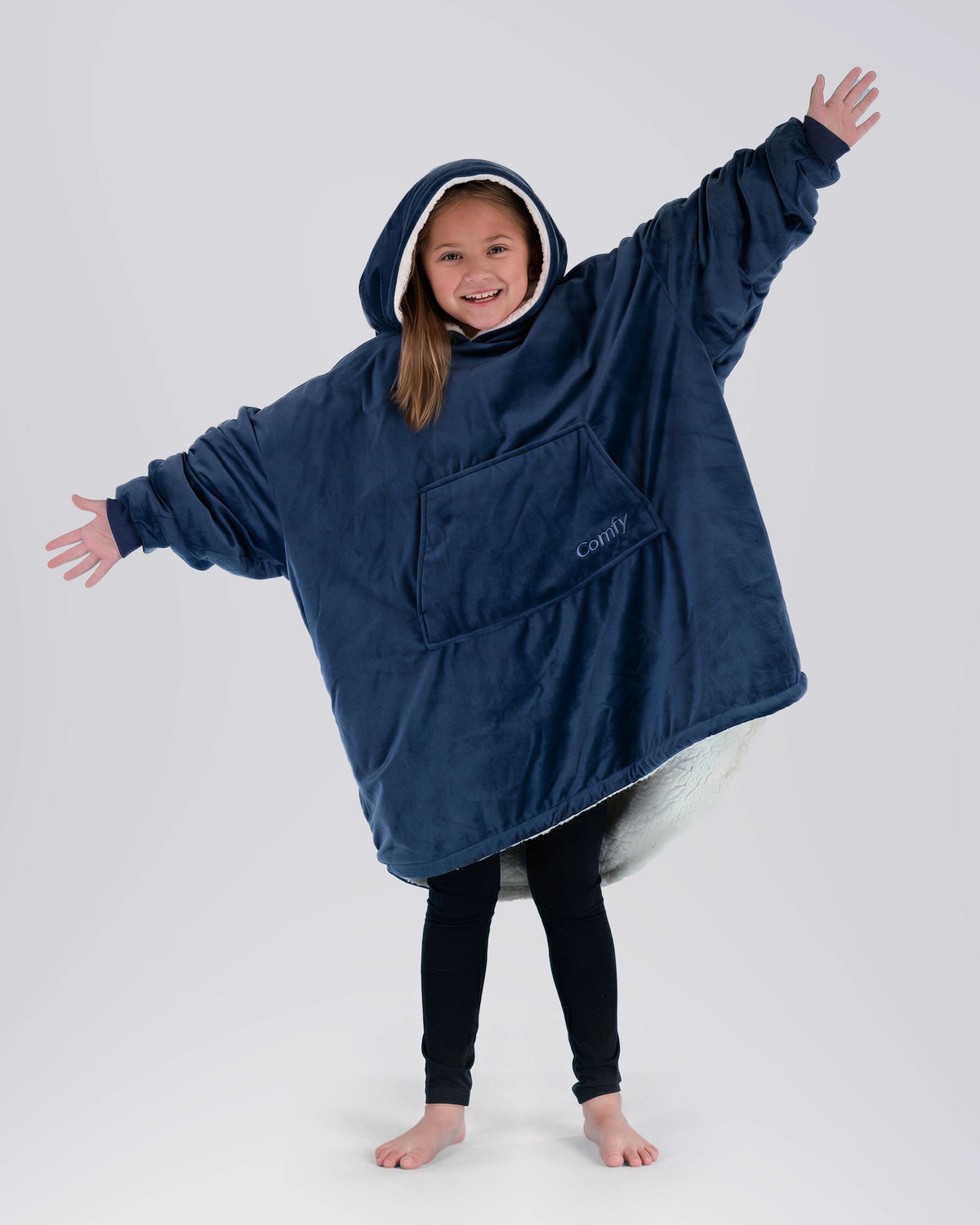 Child wearing The Original Jr. Blue wearable blanket with arms outstretched, highlighting the roomy design and oversized coverage.