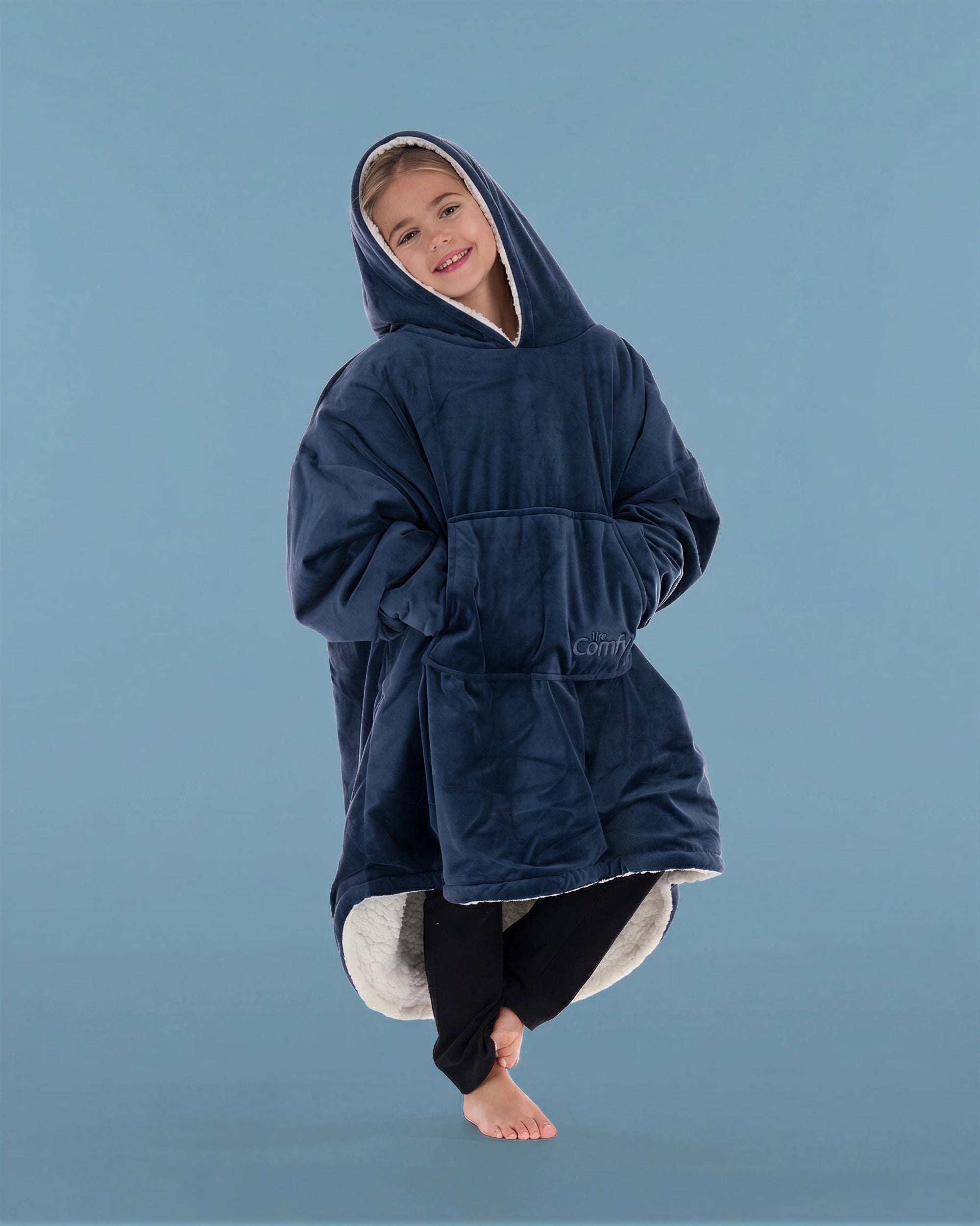 Child wearing The Original Jr. Blue wearable blanket in a relaxed pose, featuring the oversized kangaroo pocket and CloudSherpa™ lining.