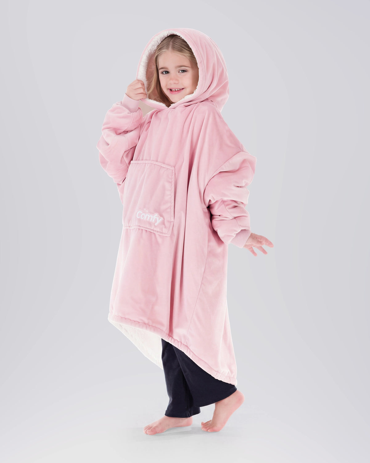 Child wearing The Original Jr. Blush wearable blanket with hood up, featuring the oversized silhouette and front kangaroo pocket.