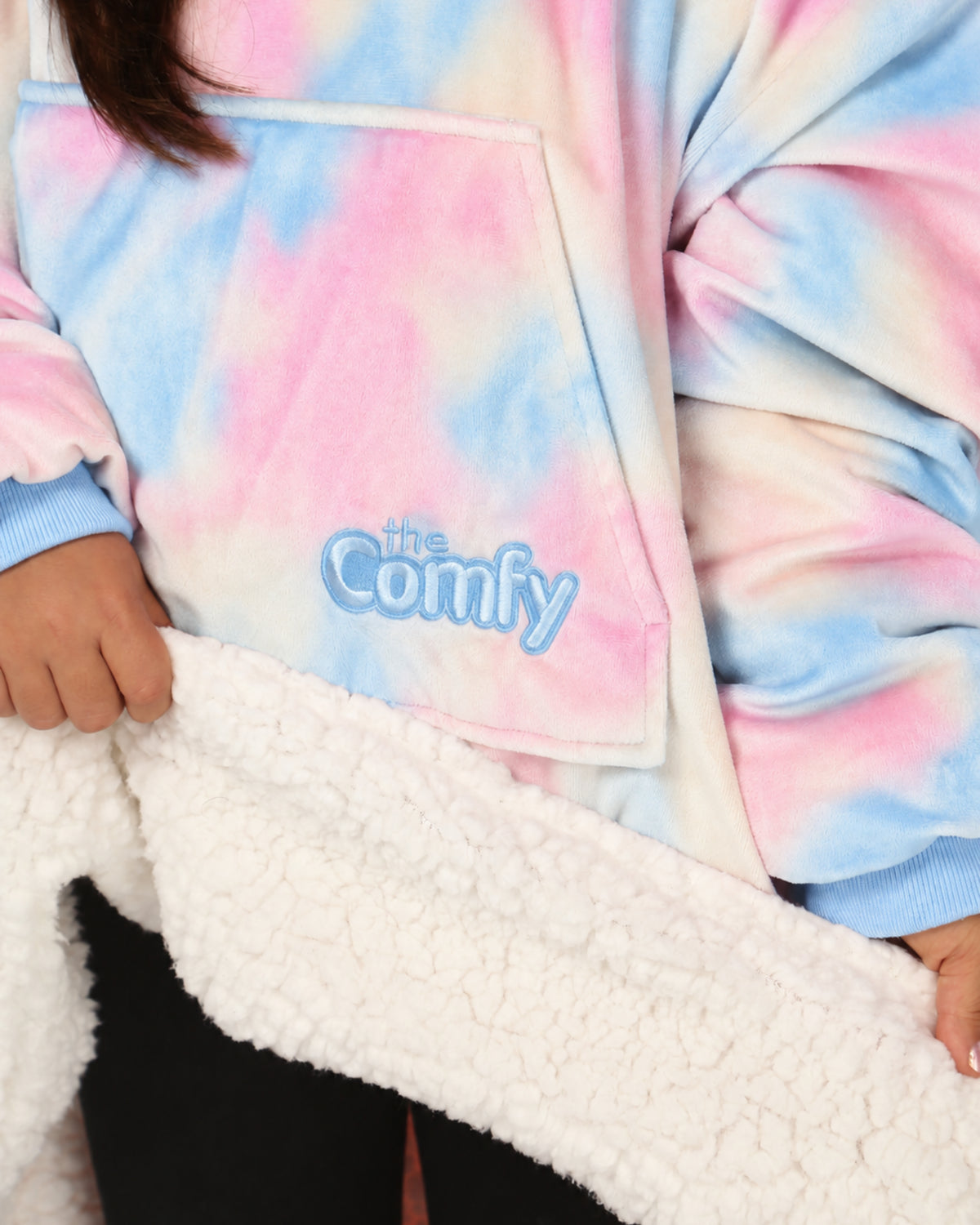 A close-up of the Original Jr. in Cotton Candy's pocket, showing the inside of the white sherpa with "The Comfy" logo embroidery.