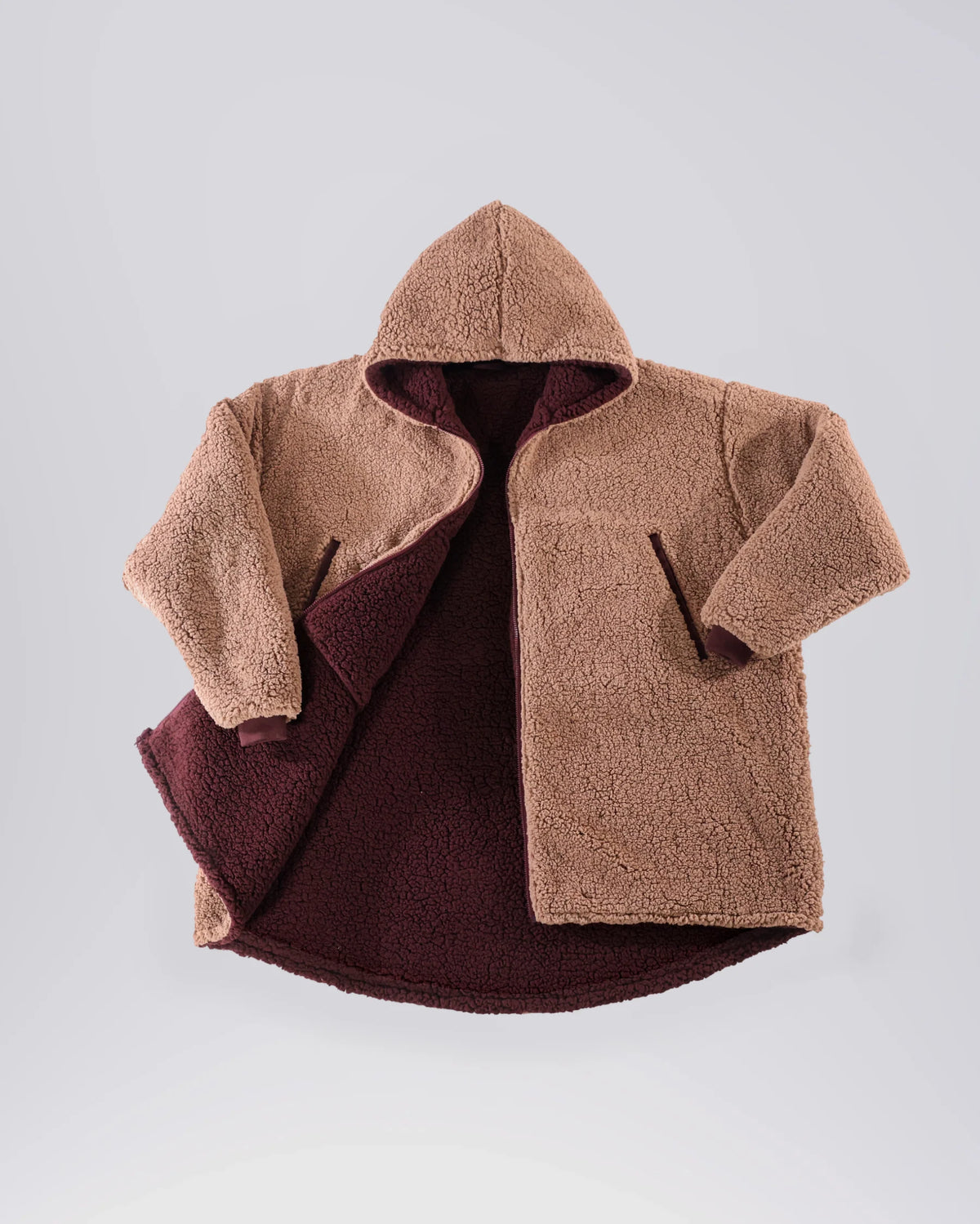 Product flat lay of the Teddy Bear Full-Zip in Camel, highlighting the all-over CloudSherpa™ texture, hood, full-length zipper, and reversible construction.