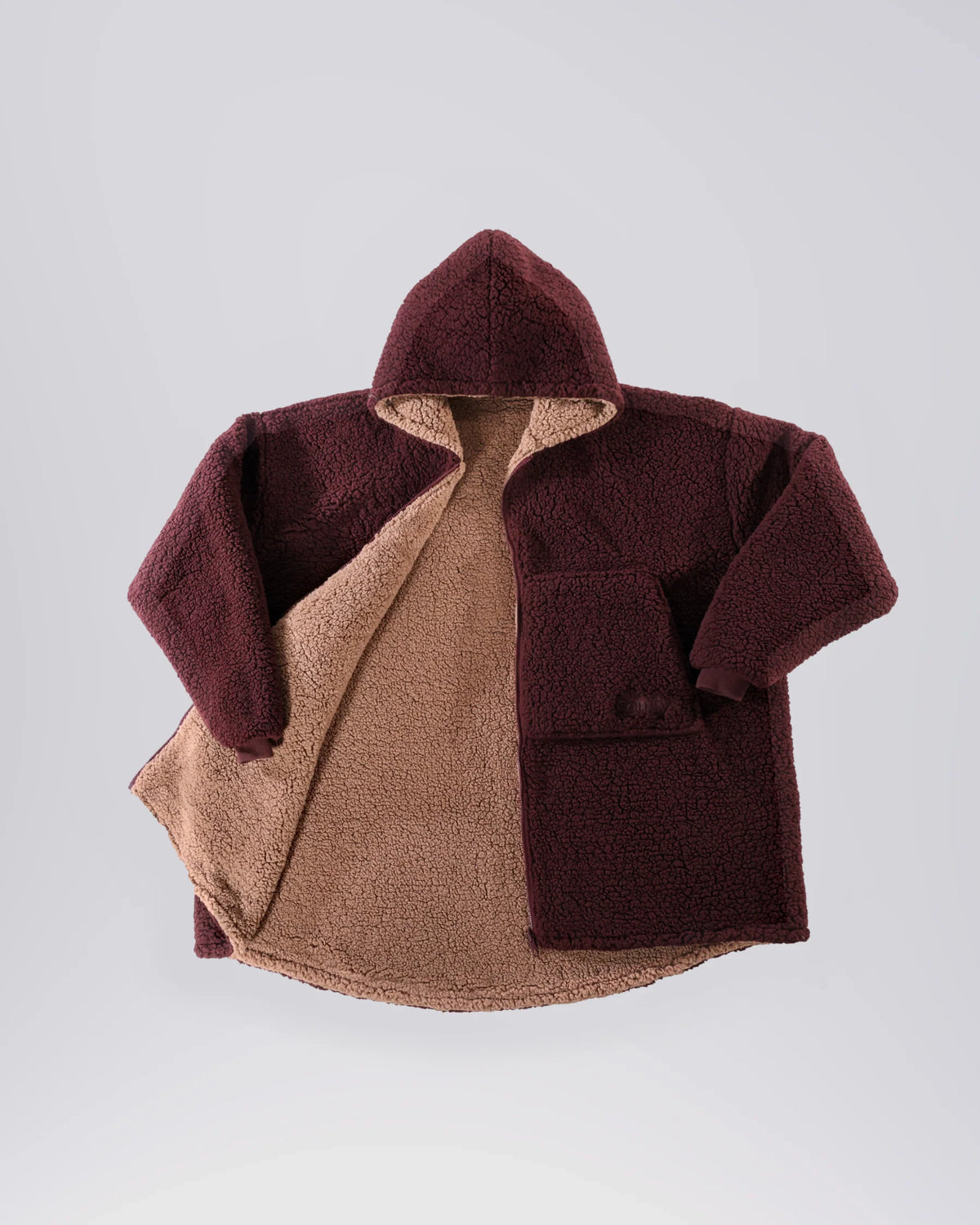Product flat lay of the Teddy Bear Full-Zip in Chocolate, displaying the reversible CloudSherpa™ interior, oversized hood, and full-zip design.