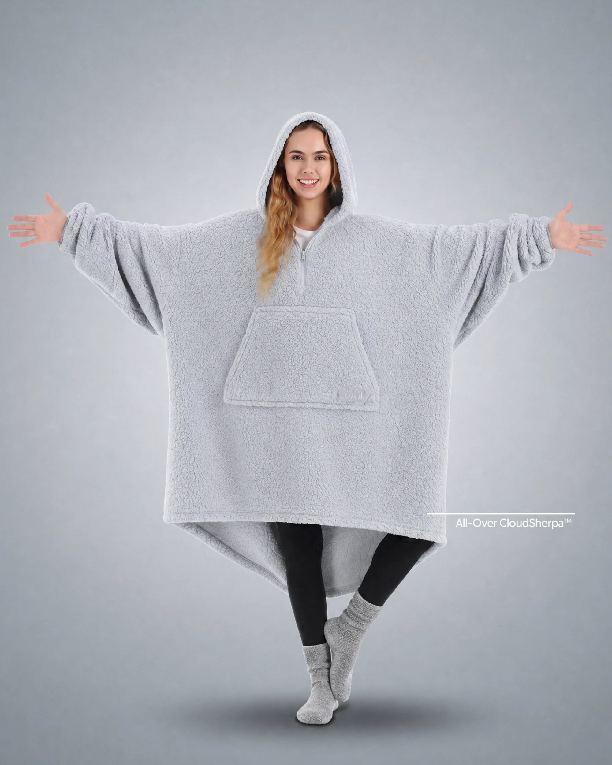 Front view of The Teddy Bear Quarter-Zip wearable blanket in light gray showing oversized fit and all-over CloudSherpa™ fabric with hood up and arms extended