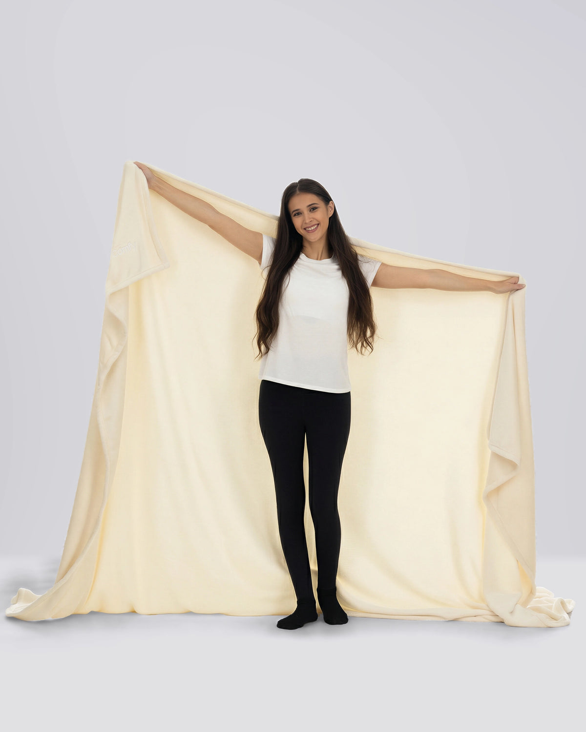 Woman standing while wrapped in The Dream Big Blanket in Cream.