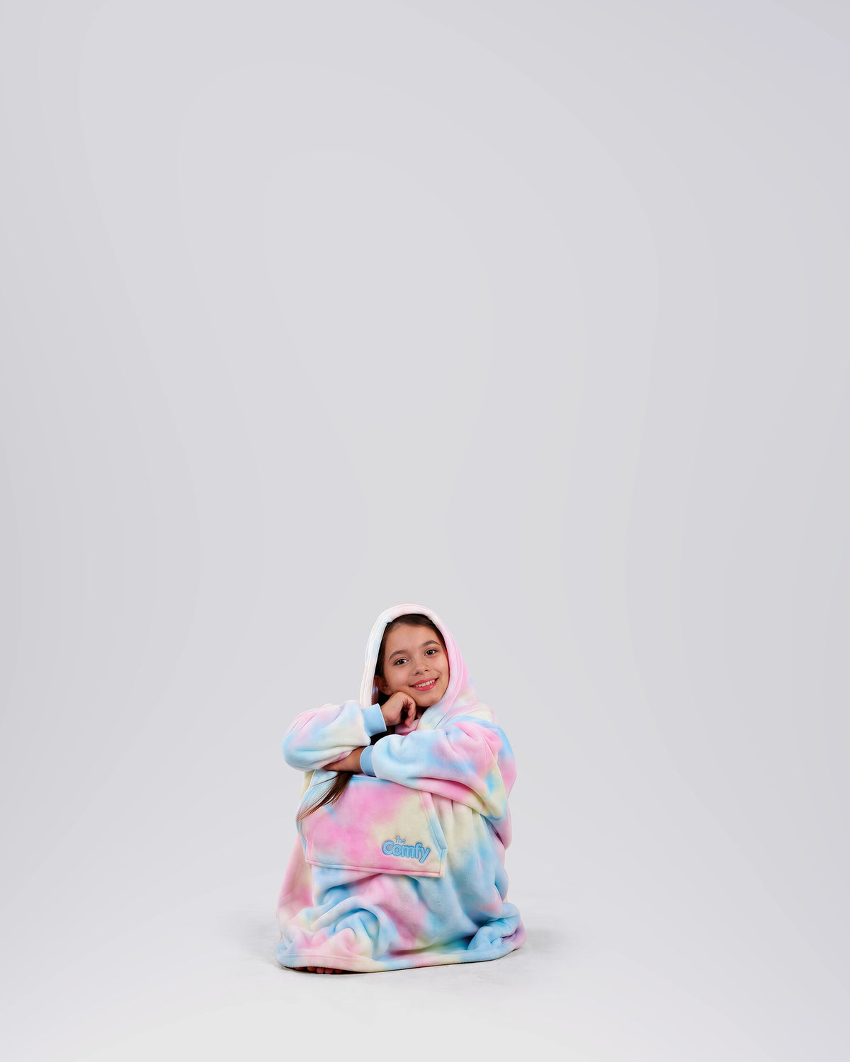 Child sitting comfortably in The Dream Jr. in Cotton Candy Tie Dye, showing its soft drape and relaxed fit.