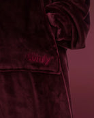 Close-up of The Dream Long in Burgundy featuring the soft microfiber fabric, front pocket, and embroidered The Comfy logo.