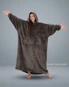 Woman standing with arms outstretched in The Dream Long wearable blanket in Dark Gray, showcasing the full-length silhouette and lightweight DreamHaven™ single-layer softness.