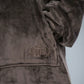 Close-up detail of The Dream Long fabric featuring the ultra-soft microfiber texture, kangaroo pocket construction, and tonal embroidered The Comfy logo.