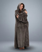 Woman wrapped comfortably in The Dream Long wearable blanket, emphasizing the extended length, oversized sleeves, and lightweight comfort for relaxing at home.