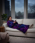 Woman relaxing on a couch in The Dream Long in Galaxy while using her phone, showcasing cozy comfort on a rainy day indoors.