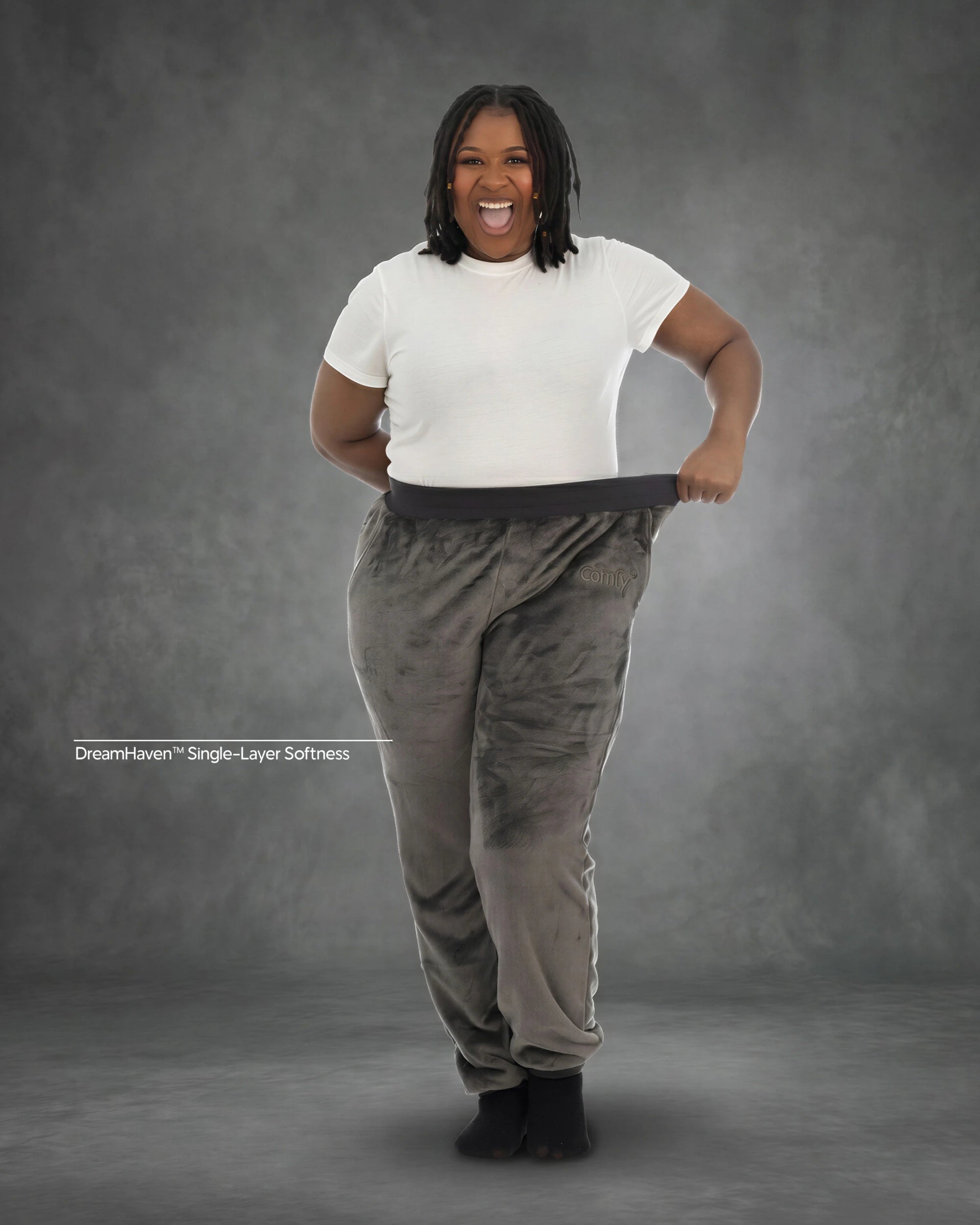 Woman stretching the waistband of Dream Pants in Dark Gray, highlighting the relaxed fit, soft Dream fabric, and comfortable elastic waistband.