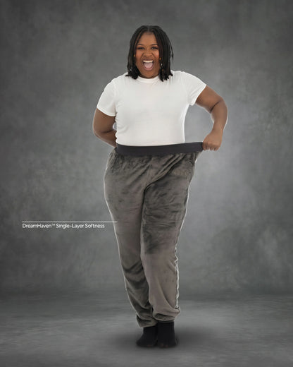 Woman stretching the waistband of Dream Pants in Dark Gray, highlighting the relaxed fit, soft Dream fabric, and comfortable elastic waistband.