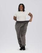 Woman stretching the waistband of Dream Pants in Dark Gray, highlighting the relaxed fit, soft Dream fabric, and comfortable elastic waistband.