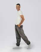 Man wearing Dream Pants in Dark Gray in side profile, showcasing the relaxed fit, side pockets, and tapered leg design.
