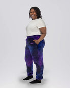 Woman wearing Dream Pants in Galaxy, showcasing the relaxed fit, side pockets, and all-over purple and blue cosmic print.