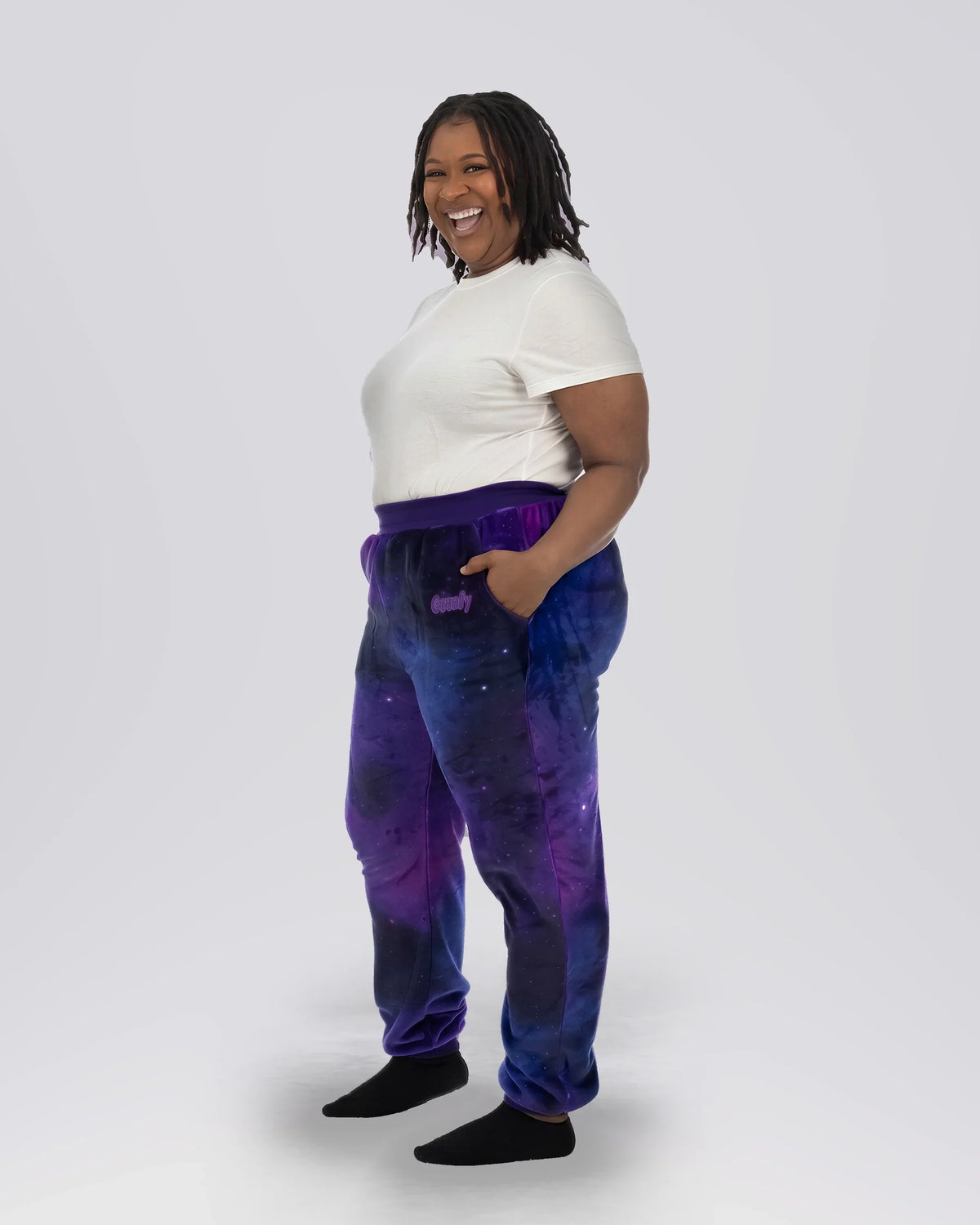 Woman wearing Dream Pants in Galaxy, showcasing the relaxed fit, side pockets, and all-over purple and blue cosmic print.
