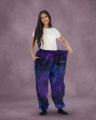 Woman stretching the waistband of Dream Pants in Galaxy, highlighting the comfortable fit and celestial-inspired print.