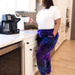 Woman wearing Dream Pants in Galaxy while holding a coffee mug in the kitchen, showcasing everyday comfort and cozy loungewear style.
