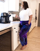 Woman wearing Dream Pants in Galaxy while holding a coffee mug in the kitchen, showcasing everyday comfort and cozy loungewear style.
