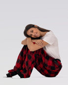Woman sitting with knees hugged while wearing Dream Pants in Red Plaid, showcasing the cozy fit and soft plaid fabric.