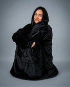 Model wrapped in The Dream wearable blanket in Black, highlighting the cozy oversized fit and relaxed comfort perfect for unwinding at home.