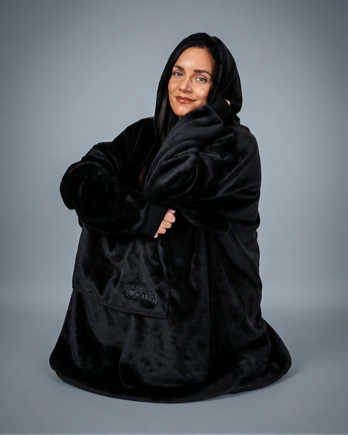 Model wrapped in The Dream wearable blanket in Black, highlighting the cozy oversized fit and relaxed comfort perfect for unwinding at home.