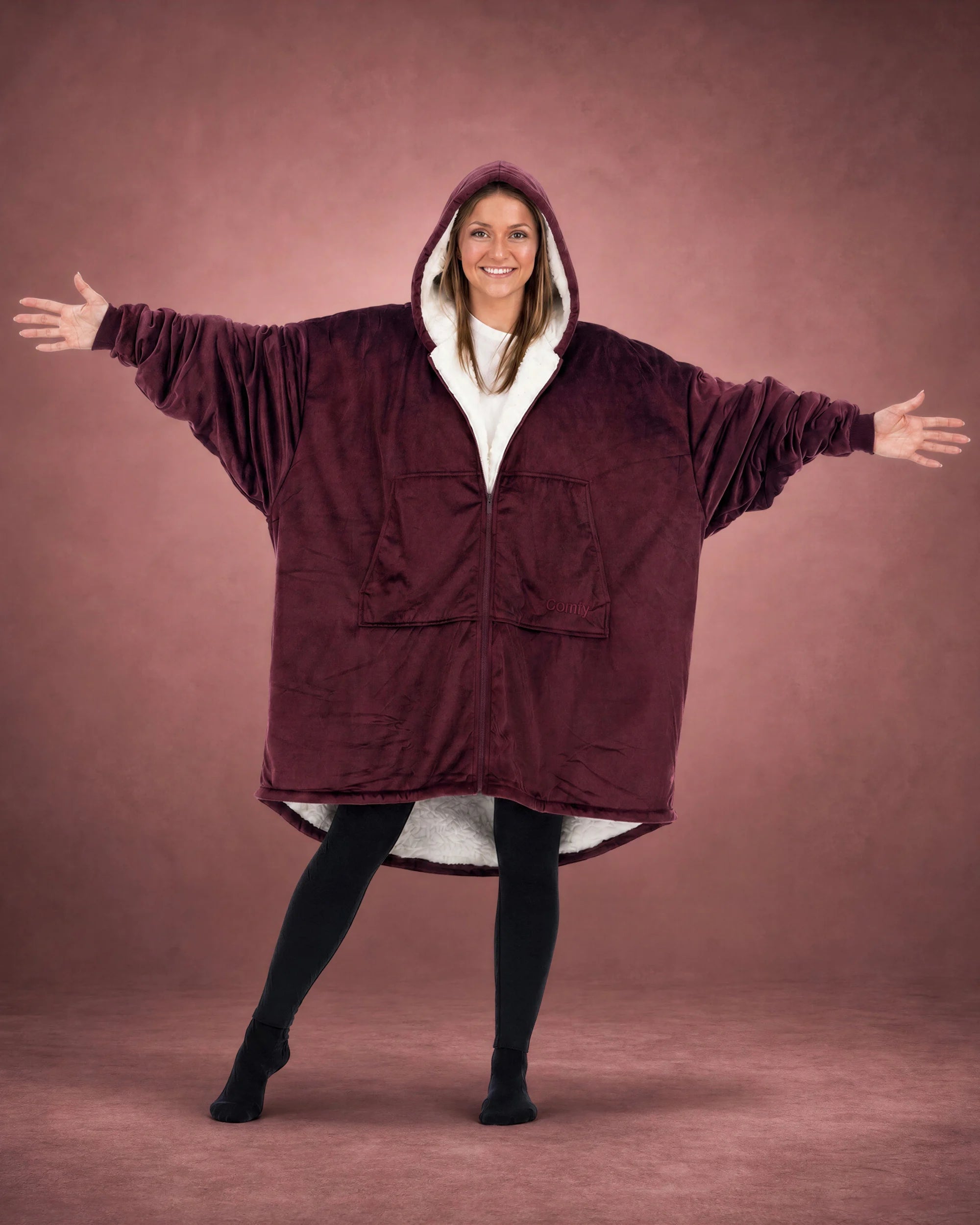 Person wearing The Original Full-Zip wearable blanket in Burgundy with arms outstretched, showcasing oversized fit and full-length zipper.