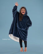 Child wearing The Original Jr. wearable blanket in Blue with CloudSherpa™ lining, waving and showing the oversized fit designed for cozy comfort.