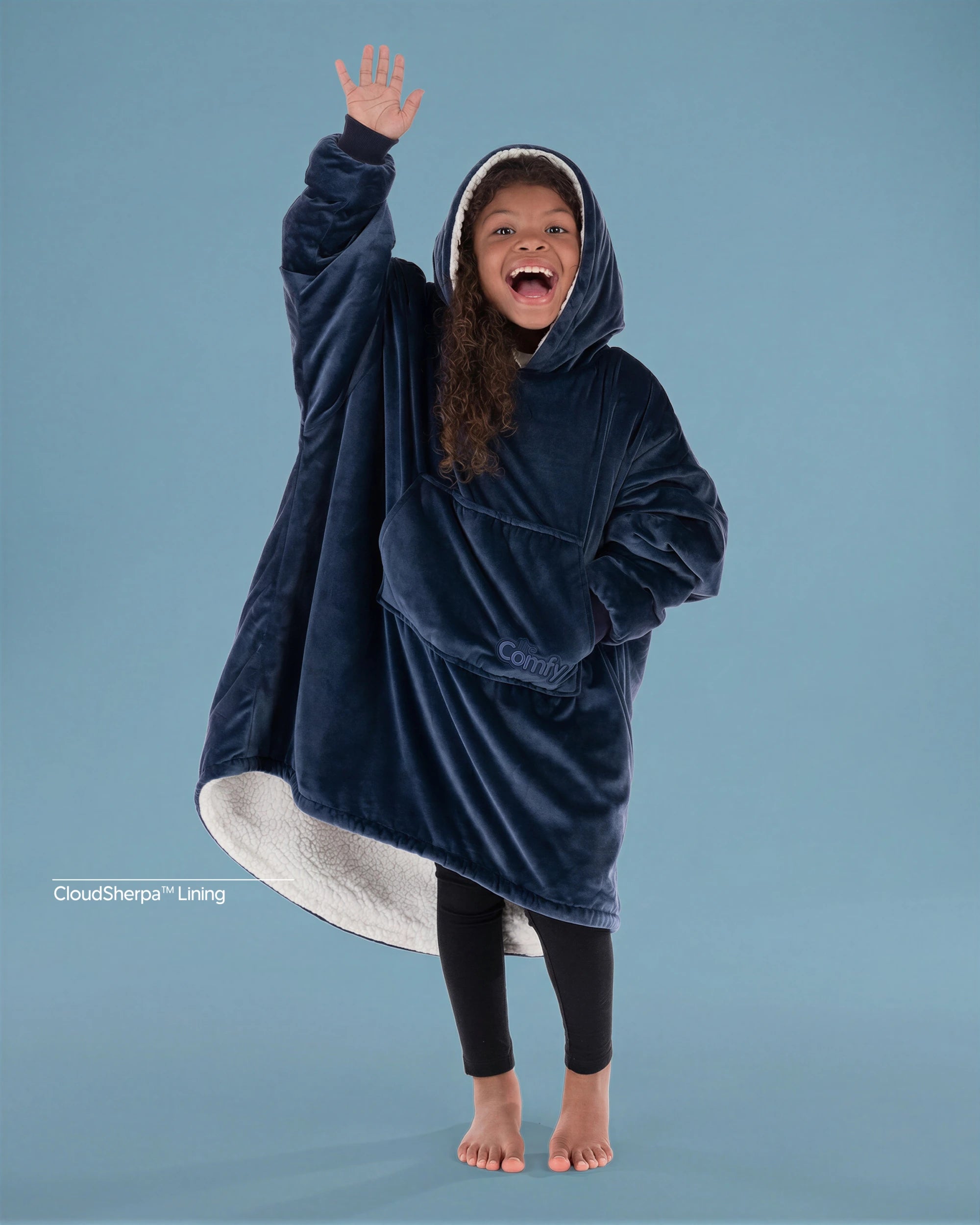Child wearing The Original Jr. wearable blanket in Blue with CloudSherpa™ lining, waving and showing the oversized fit designed for cozy comfort.
