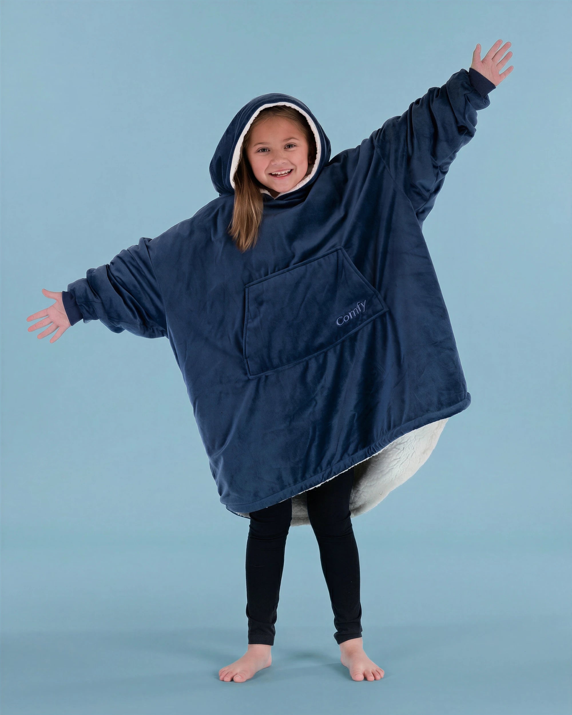 Child wearing The Original Jr. Blue wearable blanket with arms outstretched, highlighting the roomy design and oversized coverage.