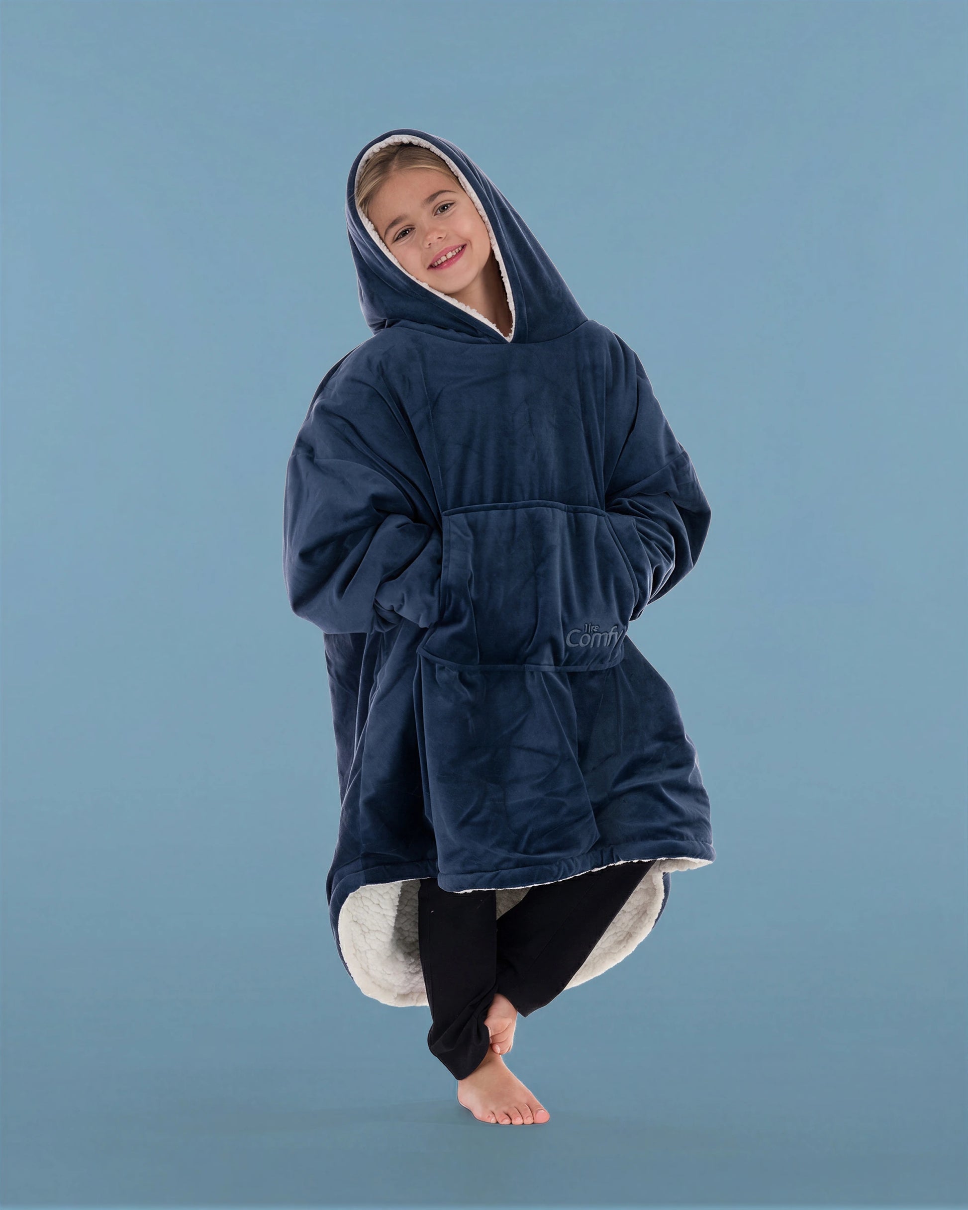 Child wearing The Original Jr. Blue wearable blanket in a relaxed pose, featuring the oversized kangaroo pocket and CloudSherpa™ lining.