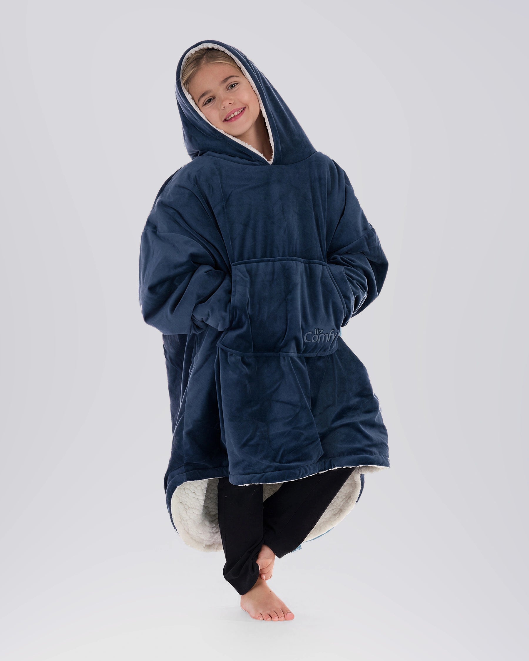 Child wearing The Original Jr. Blue wearable blanket in a relaxed pose, featuring the oversized kangaroo pocket and CloudSherpa™ lining.