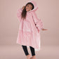 Child wearing The Original Jr. Blush wearable blanket in a playful pose, highlighting the oversized fit and soft hood.