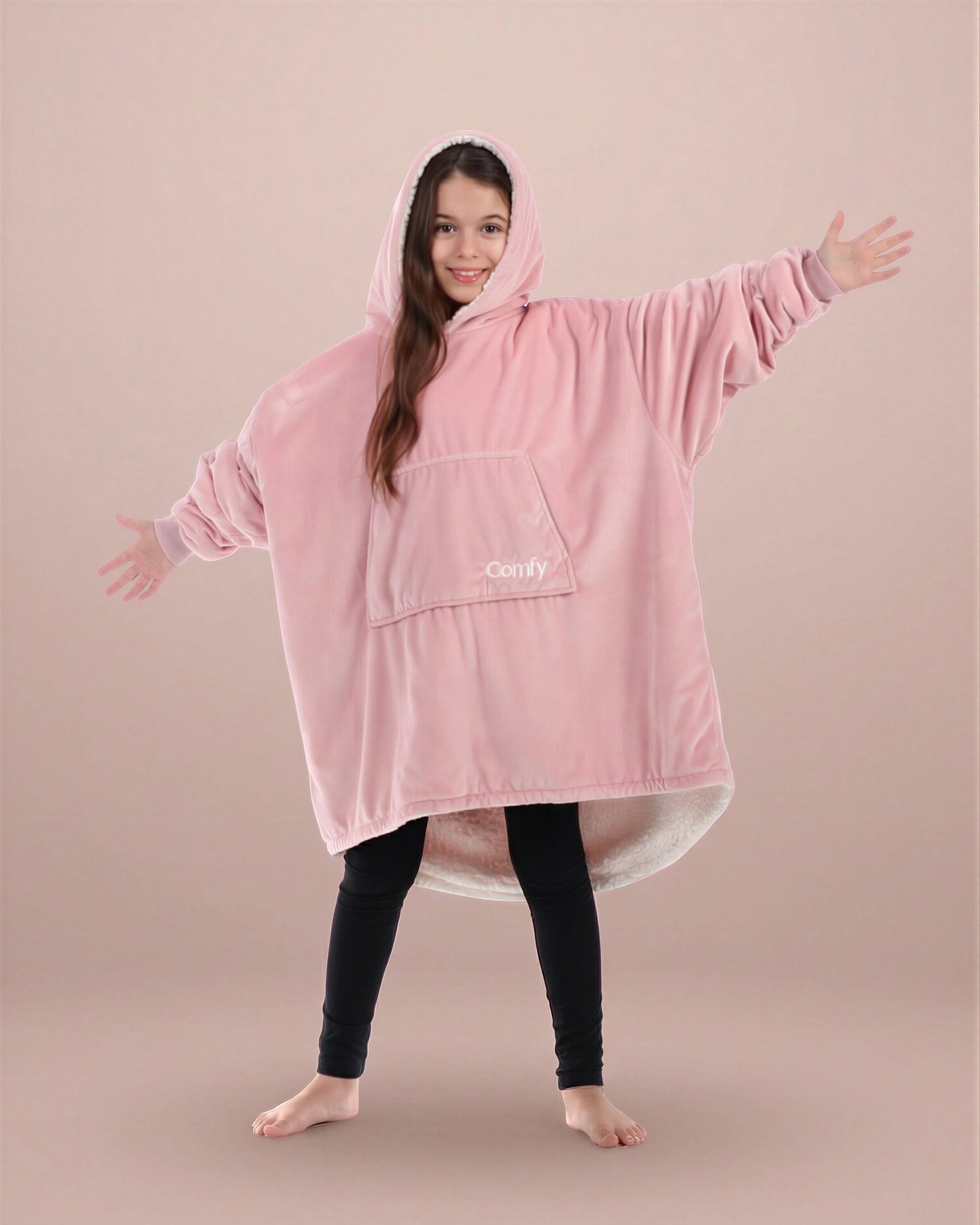 Child wearing The Original Jr. Blush wearable blanket with arms outstretched, showcasing roomy coverage and cozy comfort.