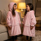 Two children wearing The Original Jr. Blush wearable blankets indoors, sharing a playful and cozy moment together.