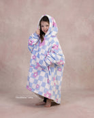 Child wearing The Original Jr. Flower Checkered wearable blanket with CloudSherpa™ lining, showcasing the playful checkered floral pattern and oversized fit.
