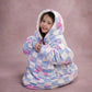 Child sitting comfortably in The Original Jr. Flower Checkered wearable blanket, highlighting full-body warmth and cozy coverage.