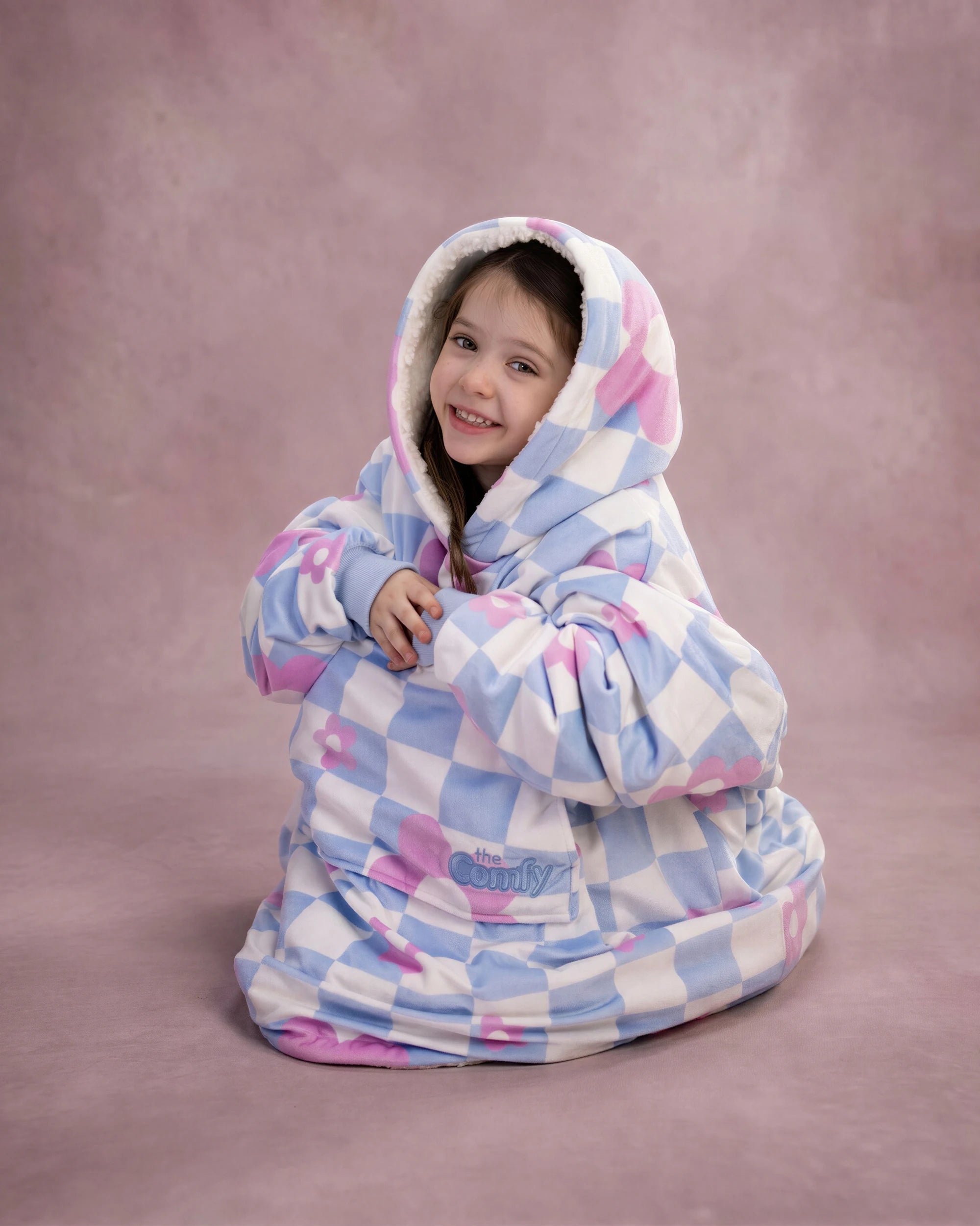 Child sitting comfortably in The Original Jr. Flower Checkered wearable blanket, highlighting full-body warmth and cozy coverage.