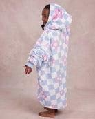 Side and back view of a child wearing The Original Jr. Flower Checkered wearable blanket, showcasing the oversized silhouette and hood design.