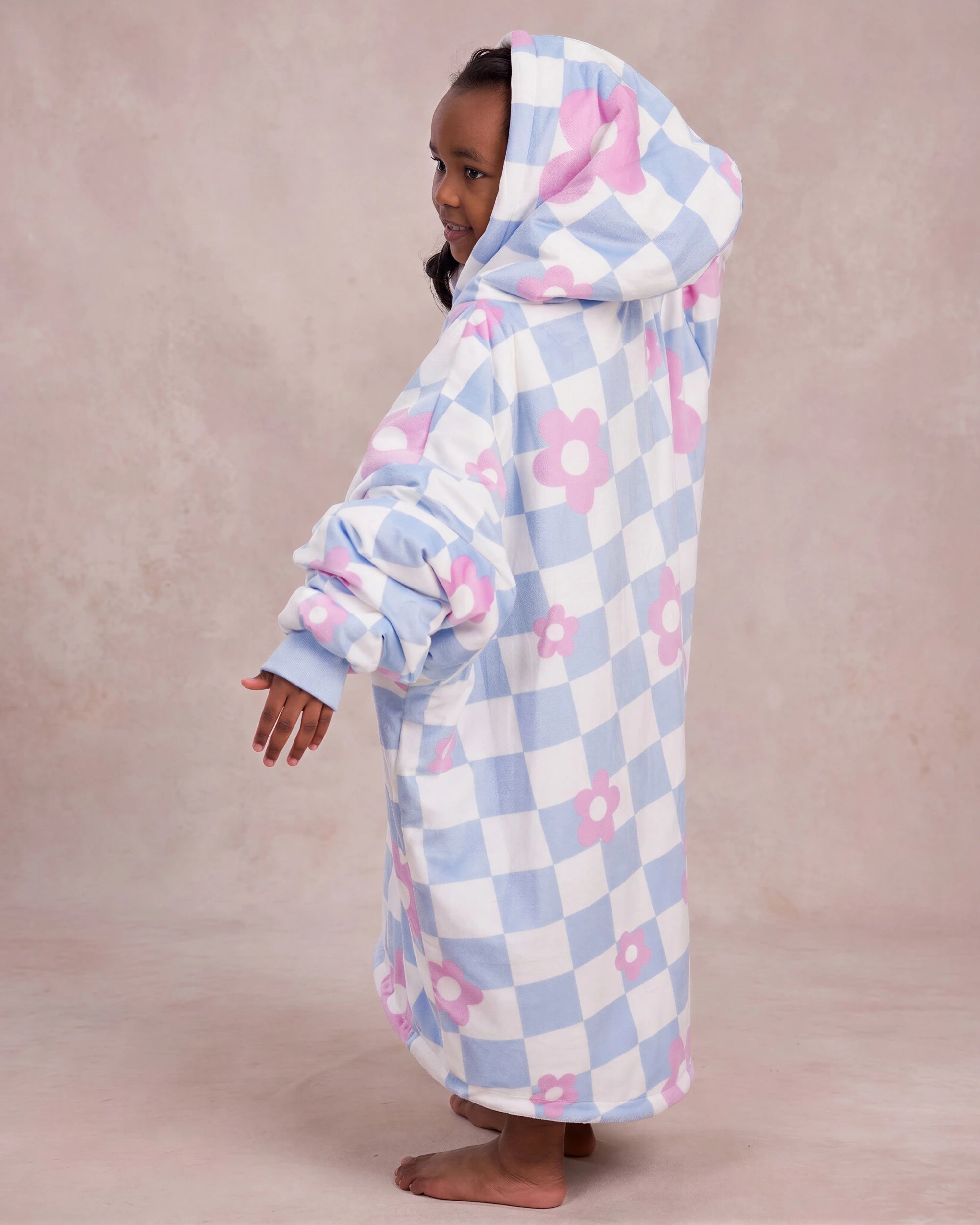 Side and back view of a child wearing The Original Jr. Flower Checkered wearable blanket, showcasing the oversized silhouette and hood design.