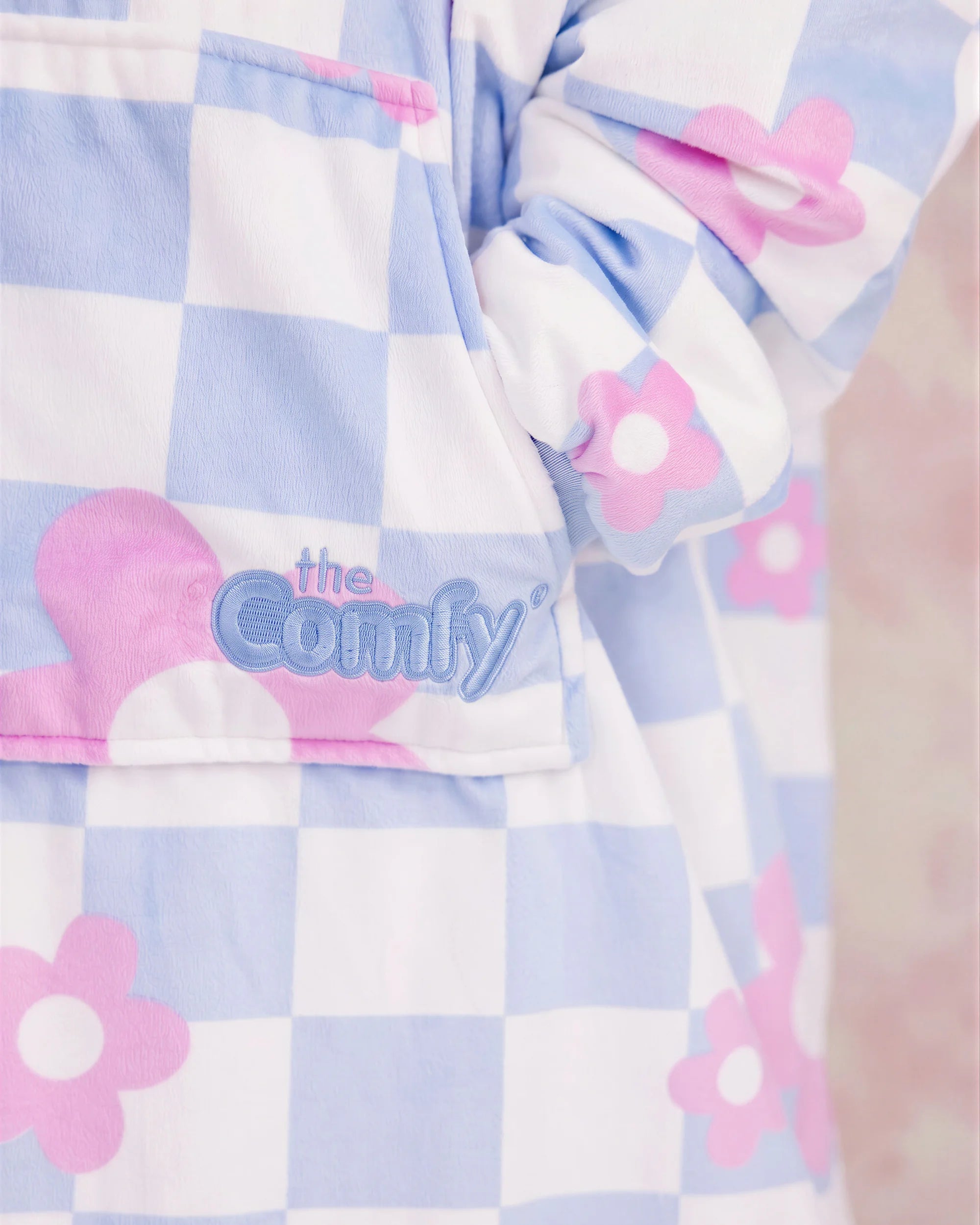 Close-up of The Original Jr. Flower Checkered wearable blanket, highlighting the soft fabric, floral checkered pattern, and embroidered logo detail.