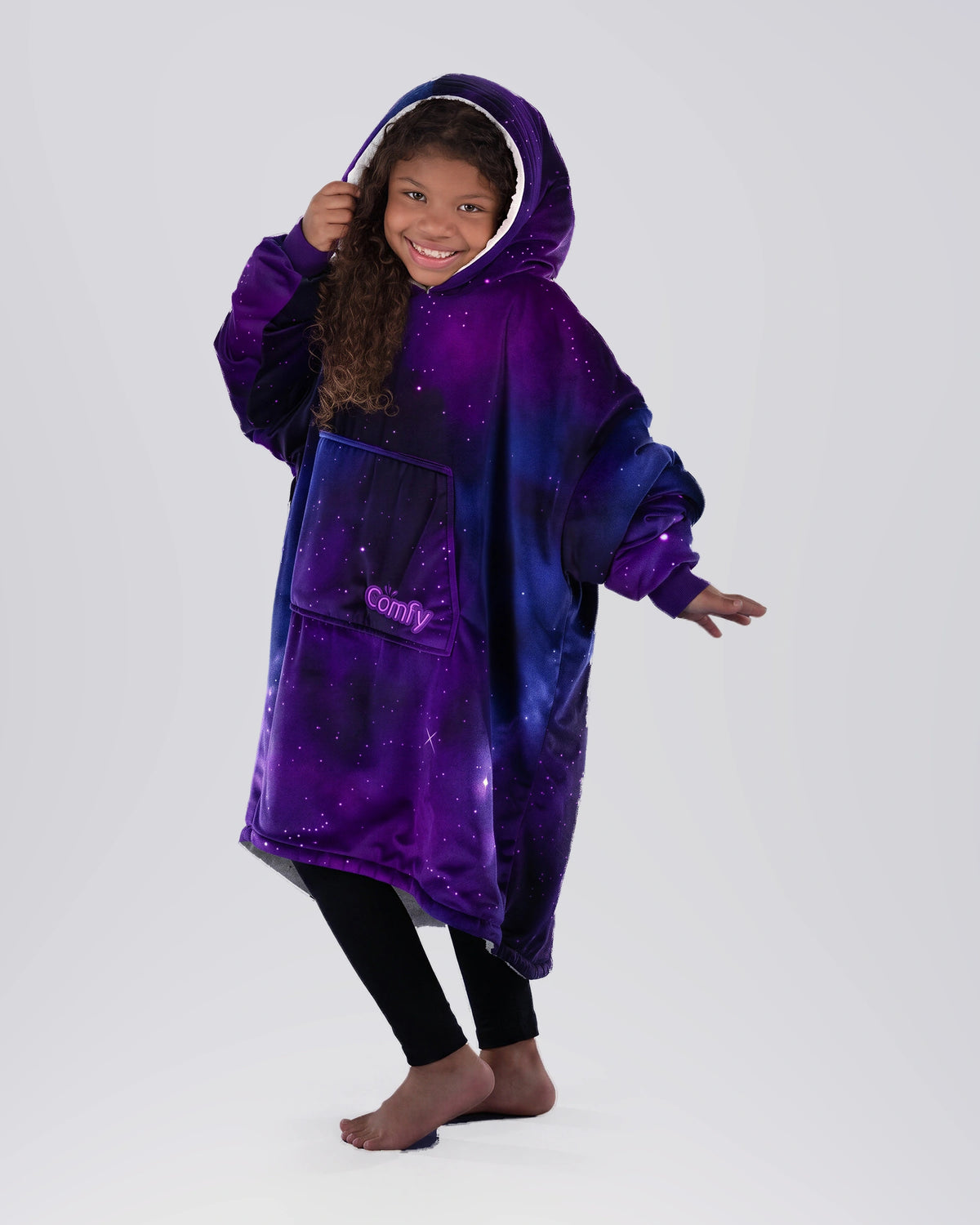 Child wearing The Original Jr. Galaxy wearable blanket in a playful pose, highlighting the oversized hood, kangaroo pocket, and cozy comfort.